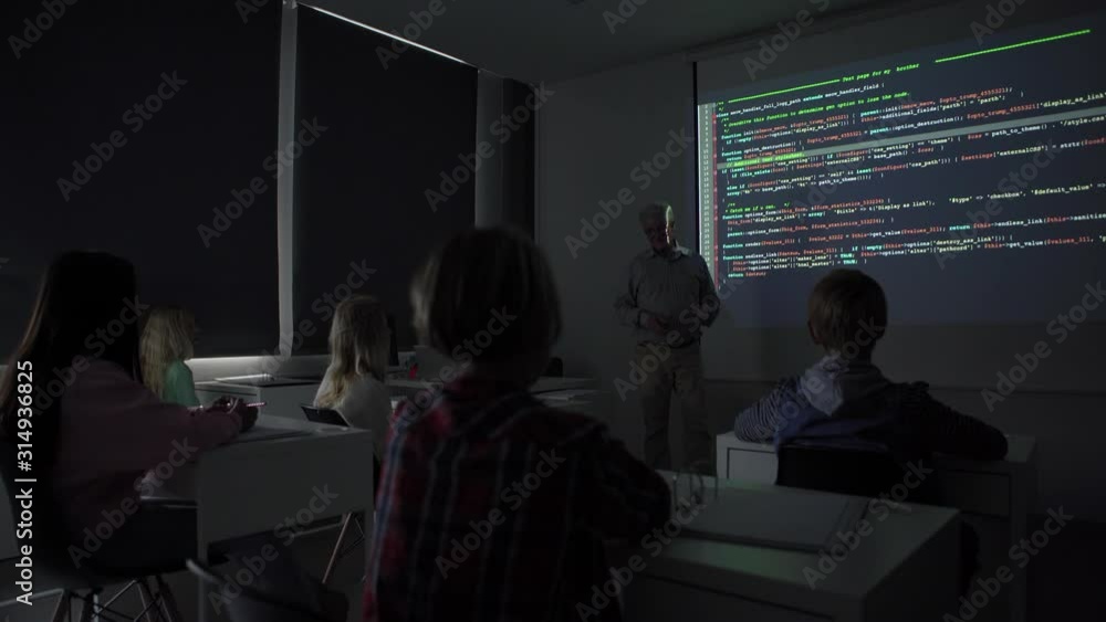 Wall mural tilt down view of mature teacher talking to audience while teaching kids programming during computer