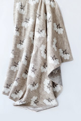 Knitted plaid falls of the folds. It has a pattern in the form of white cotton boxes.