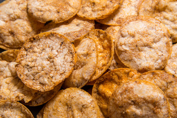 Top view pile of organic, crispy, baked, whole grain rice chips with spices. Gluten free healthy snack. Food background