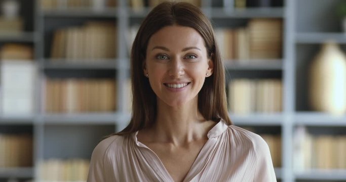 Smiling attractive young woman looking at camera, slow motion portrait
