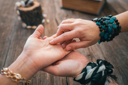 Close up of fortune teller point her finger to woman's palm line and read her fortune. Palmistry cpncept.