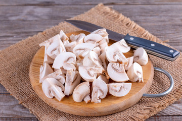 Fresh sliced champignon mushrooms on wooden board