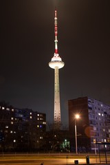 Vilnius TV Tower, Lithuania colored with white light, night, with soviet buildings, vertical