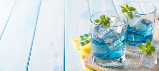 Blue lemonade in glasses on wood background, copy space