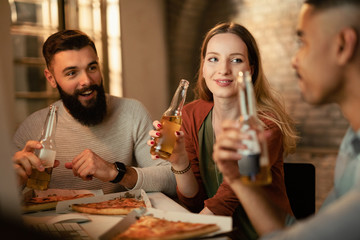 Start up team talking while drinking beer and eating pizza in the office.