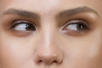 Fototapeta premium Close-up of woman's eyes with evening make-up. Fashionable shades of eye shadow, extremely long eyelashes and thick smooth eyebrows. Open beautiful look. Clean skin