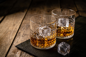 Whiskey in glasses on wood background, copy space, toned