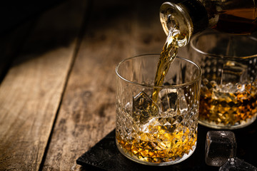 Whiskey in glasses on wood background, copy space, toned