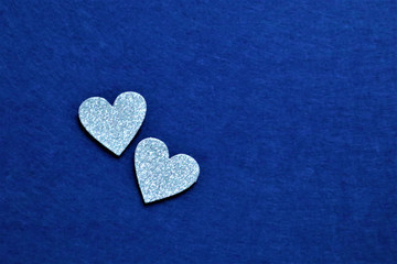 Obraz premium two silver hearts on classic blue background in trendy color of year. Copy space.