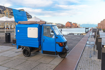 Three-wheeled mini truck parked near the sea pier