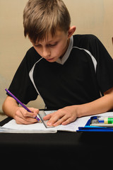 Little schoolboy bored homework in a school notebook for drawing.2020