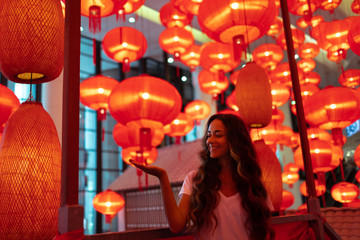 Happy tourist woman enjoying traditional red lanterns decorated for Chinese new year Chunjie....