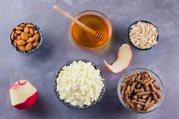 Healthy diet breakfast. Ingredients for a healthy breakfast: oatmeal, granola, honey, almonds, apple, cottage cheese. Homemade granola on a gray background. Top view