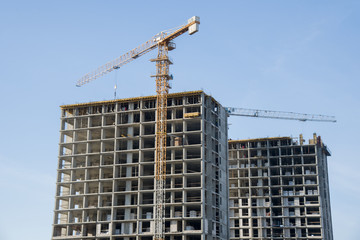 Hydraulic luffing jib tower cranes and workers being poured concrete into foundation. Cement pouring into formwork of building at construction site. Tower cranes constructing a new residential build