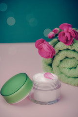 Homemade spa with cream, towel and flowers on pink with blue background