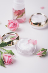 Homemade spa with rose cosmetic cream on pink background top view