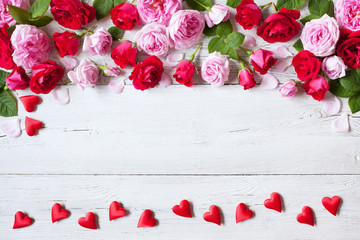 Roses and red hearts on a wooden background