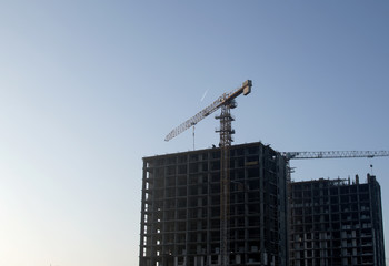 Fototapeta premium Hydraulic luffing jib tower cranes and workers being poured concrete into foundation. Cement pouring into formwork of building at construction site. Tower cranes constructing a new residential build