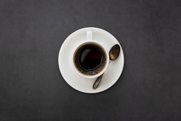 Coffee. White cup of coffee top view spoon and plate on dark background