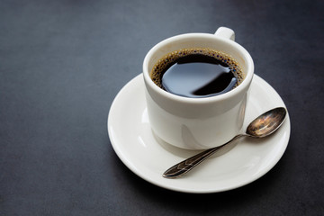 Coffee cup isolated. White cup of coffee top view spoon and plate on dark background