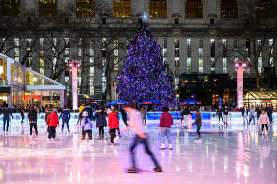 New York, New York, USA - January 10, 2020: People ice skating in the Bryant Park rink with a Christmas tree in the background.
