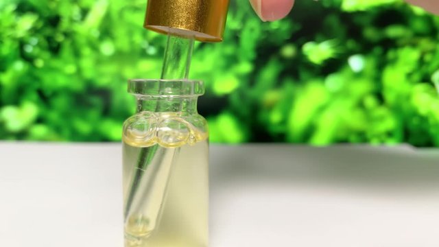 Gets oil from  bottle on  background of grass. CBD pipette.  Bottle of Cannabis oil. Oil bottles on white background. Medical cannabis concept. Spruce cbd oil. Oil cbd stock images 