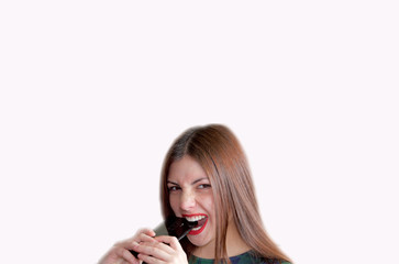 Hysterical young woman with red painted lips and loose hair biting a mobile phone