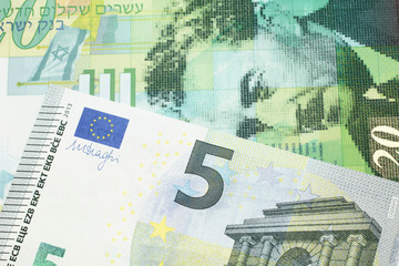A twenty shekel note from Israel close up in macro with a blue and green, European five euro bank note