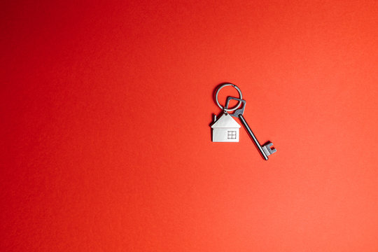 Key with key chain in form of house on a red background