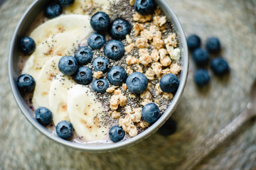 Healthy breakfast berry smoothie bowl topped with banana, granola, Blueberries and chia seeds with copy space