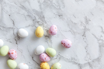 Fototapeta na wymiar Happy Easter concept. Preparation for holiday. Easter pastel candy chocolate eggs sweets on trendy gray marble background. Simple minimalism flat lay top view copy space.