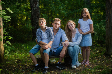 Happy family outdoors spending time together. Father, mother, daughter and son are having fun in a summer park at summer