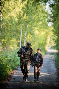 Father and son together hunting together. Walking the road in a forest.