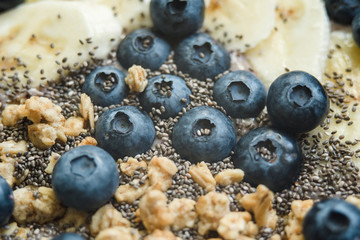 Healthy breakfast berry smoothie bowl topped with banana, granola, Blueberries and chia seeds with copy space