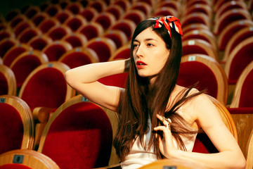 portrait of a pretty girl hipster in a movie theater posing in fashion style, dreaming alone
