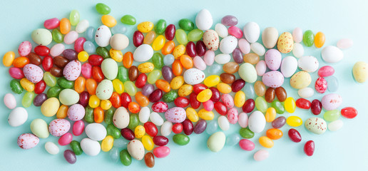 Happy Easter concept. Preparation for holiday. Easter candy chocolate eggs and jellybean sweets isolated on trendy pastel blue background. Simple minimalism flat lay top view copy space.