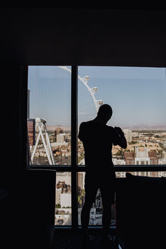 Silhouette d'un homme regardant la grande roue de Las Vegas &agrave; travers la fen&ecirc;tre de l'h&ocirc;tel 