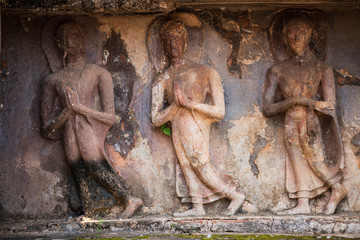 Fototapeta na wymiar Walking Buddha image at Wat Mahathat. The base of the main chedi is decorated with relief-stucco of 168 Buddhist disciples walking with their hands clasped together. Sukhothai Historic Park