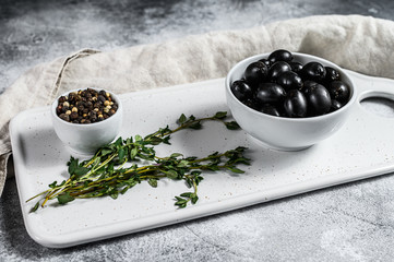 Fototapeta na wymiar Black olives on a white chopping Board. Gray background. Top view