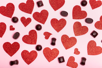 Fototapeta na wymiar Valentine`s day poster with red hearts and chocolate candies on a pink background