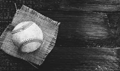 Baseball on texture of burlap and wood in black and white.
