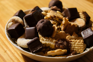 Hand made biscuits with chocolate icing in a bowl on a wooden table.