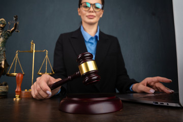 Woman in stylish glasses writing notary in textbook during online learning on laptop computer, sitting in restaurant interior. Female marketing coordinator using diary for work