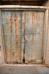 Fototapeta na wymiar Eine geschlossene, altertümliche, verfallene Haustür in der verlassenen Stadt Al Hamra im Oman aus Holz.