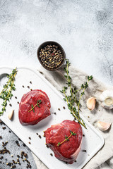 Raw filet Mignon steak on a white chopping Board. Beef tenderloin. Gray background. Top view. Space for text