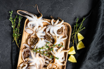Raw baby octopus with thyme and lemon. Organic seafood. Black background. Top view