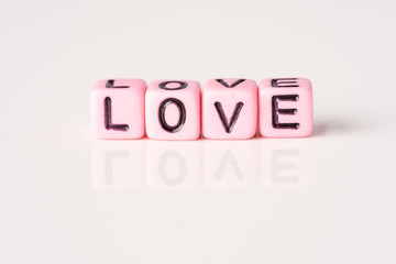 Love and Valentines Day concept: Miniature Couple with LOVE wordings on small beads on white backgrounds