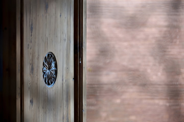 Old half-open wooden door seen through a fence with geometric patterns