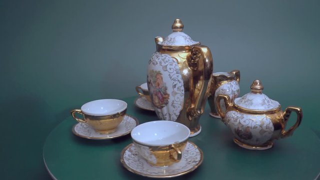Faience coffee set with teapot, milk Cup and Cup on a green background. Retro. Rotation.
