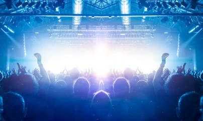 Concert stage shot from inside a concert hall with many people silhouettes attending the show,...